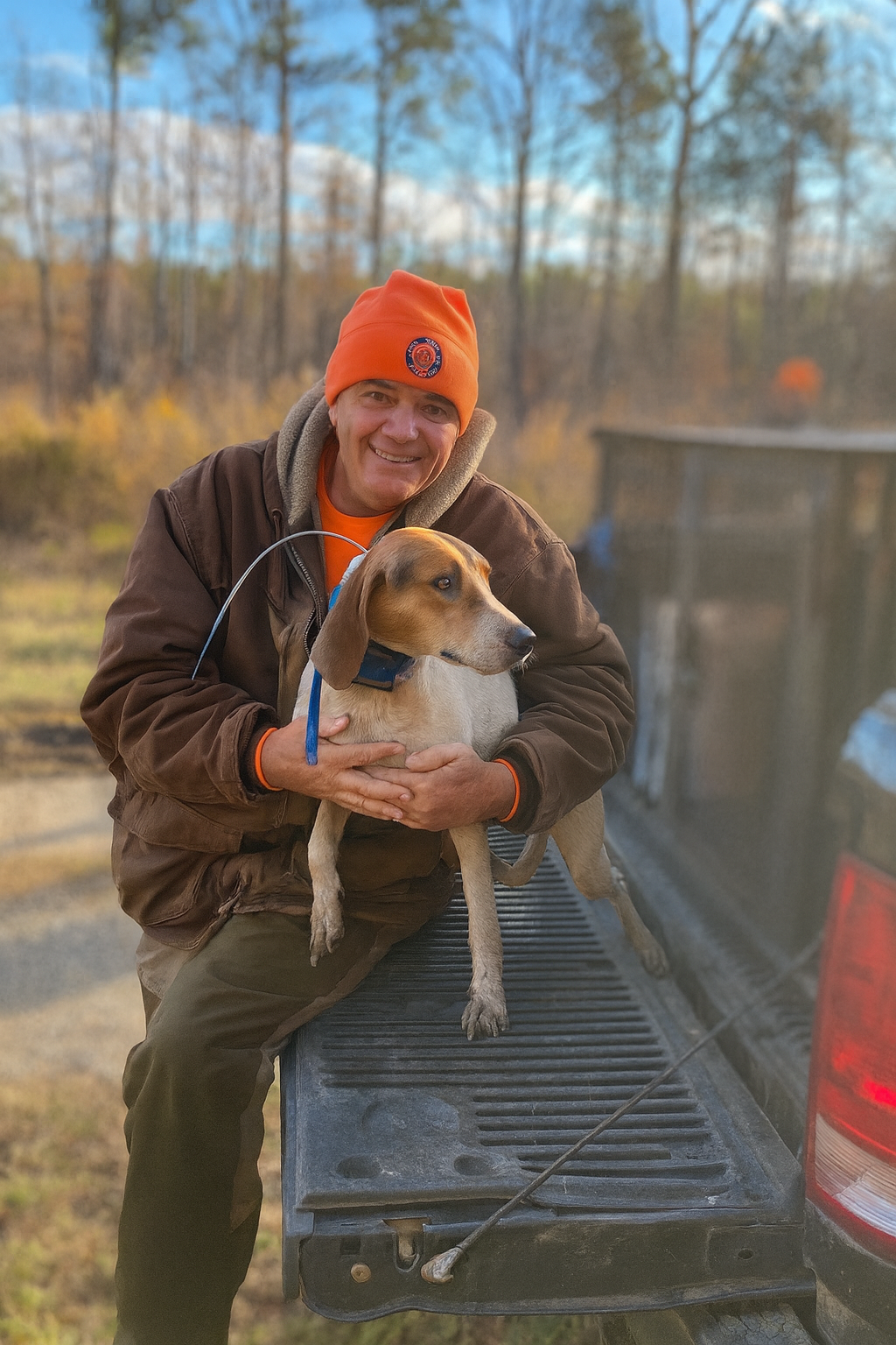 Todd on the tailgate with hound, background blurred